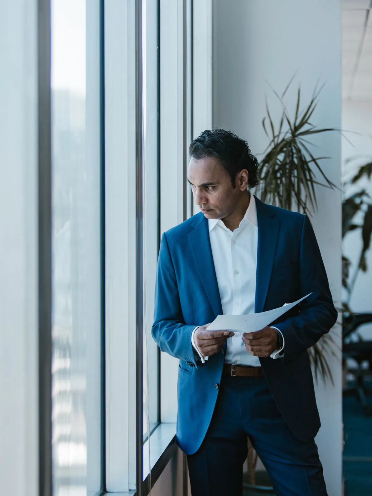 Professional portrait of an insurance advisor reviewing documents by a window